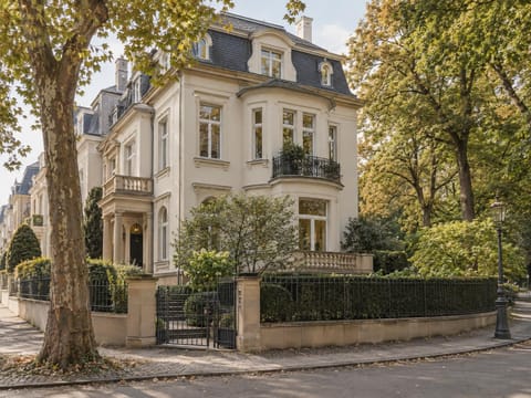 Stadtvilla mit Mansarddach am Rand eines Parks mit altem Baumbestand